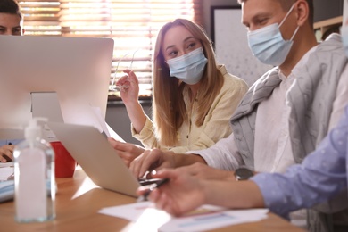 Photo of Coworkers with masks in office. Protective measure during COVID-19 pandemic