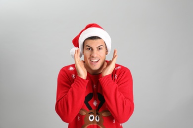 Photo of Happy man wearing Santa hat on grey background