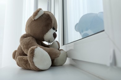 Photo of Cute lonely teddy bear on windowsill indoors. Space for text