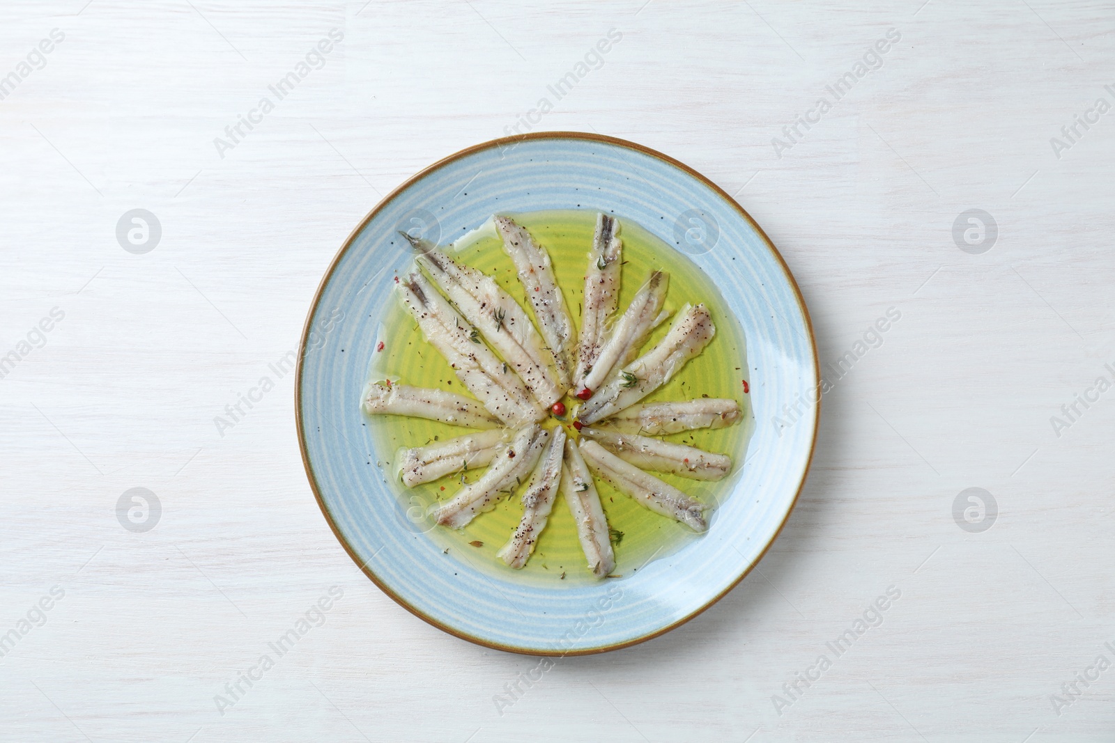 Photo of Tasty pickled anchovies with spices on white wooden table, top view