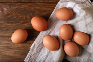 Photo of Raw brown chicken eggs on wooden table, flat lay