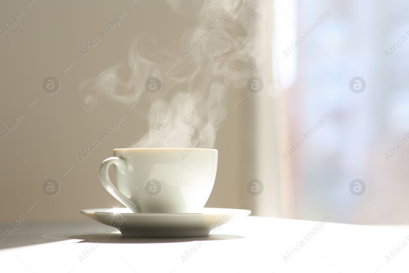 Photo of Cup of delicious coffee on sunlit table, space for text. Good morning