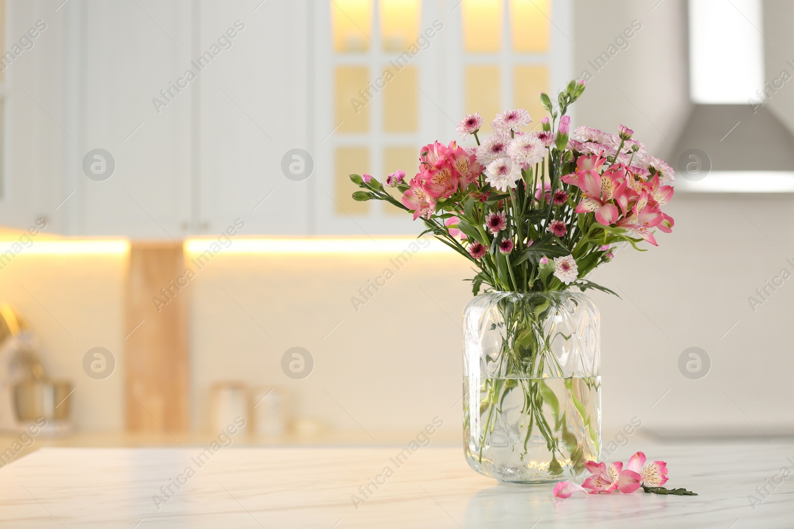 Photo of Vase with beautiful flowers on table in kitchen, space for text. Stylish element of interior design