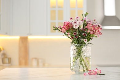 Vase with beautiful flowers on table in kitchen, space for text. Stylish element of interior design