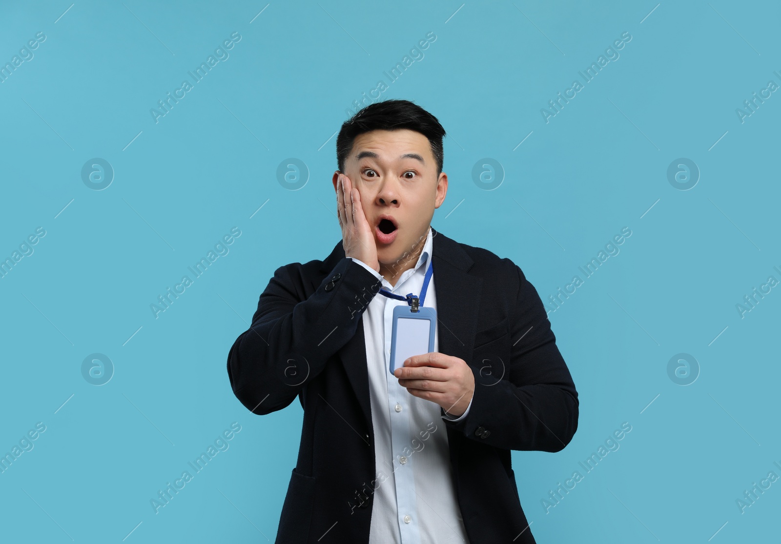 Photo of Emotional asian man with vip pass badge on light blue background