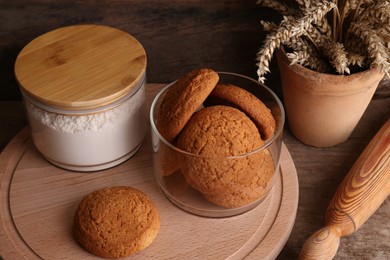 Photo of Cookies, flour and wheat spikes on wooden table