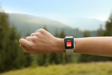 Image of Woman with smart watch checking heart rate in health monitor app outdoors, closeup