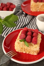 Piece of delicious Napoleon cake with fresh raspberries served on grey table, closeup