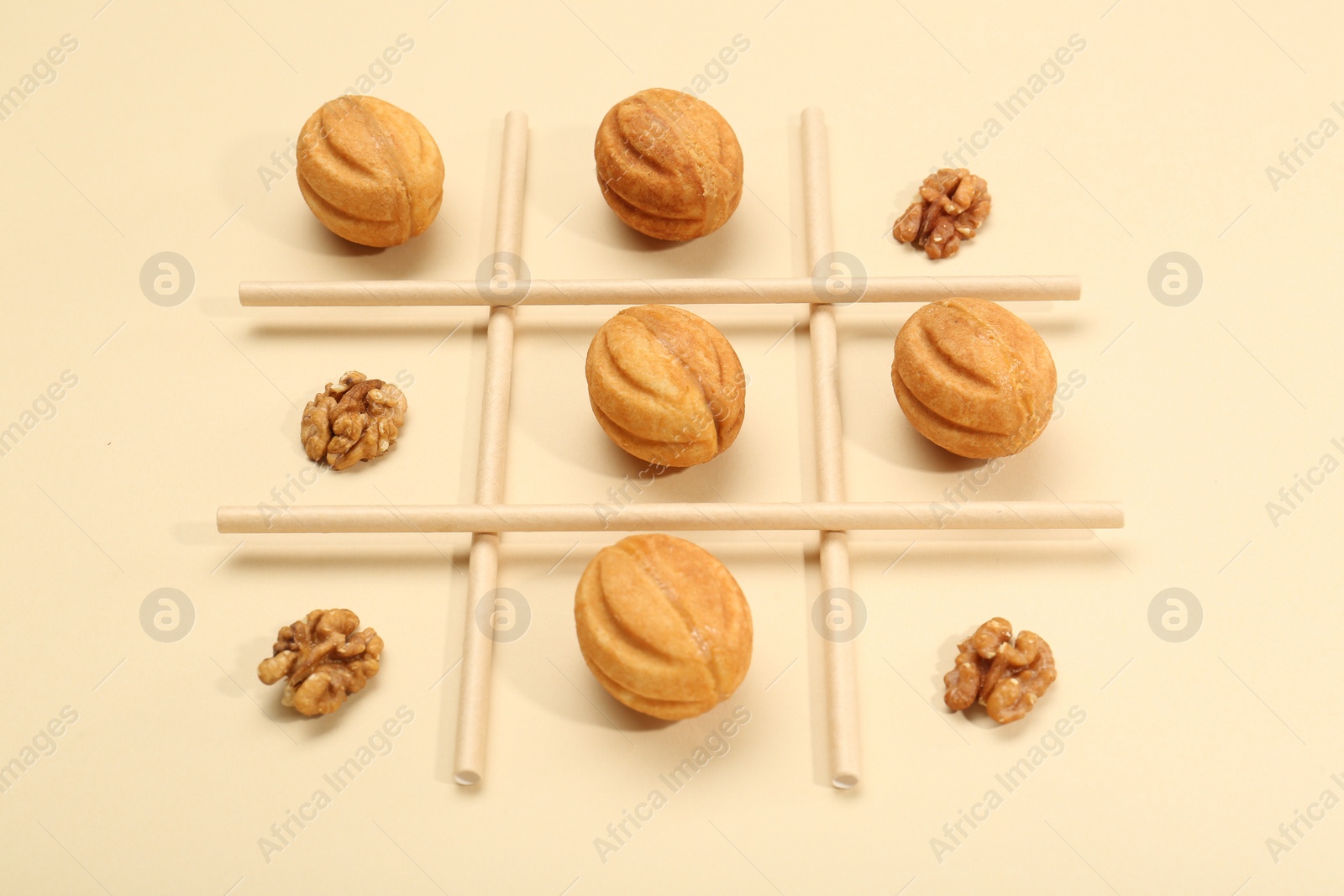 Photo of Tic tac toe game made with walnuts and cookies on beige background