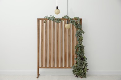 Photo of Stylish photo zone with wooden screen, floral decor and pendant lamps indoors