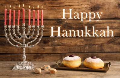 Image of Happy Hanukkah. Silver menorah, sufganiyot and dreidels on wooden background