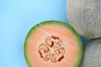 Whole and cut fresh ripe cantaloupe melons on light blue background, flat lay