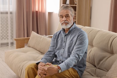 Senior man on beige sofa at home