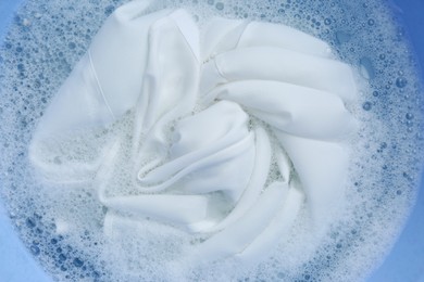 White clothing in suds, top view. Hand washing laundry