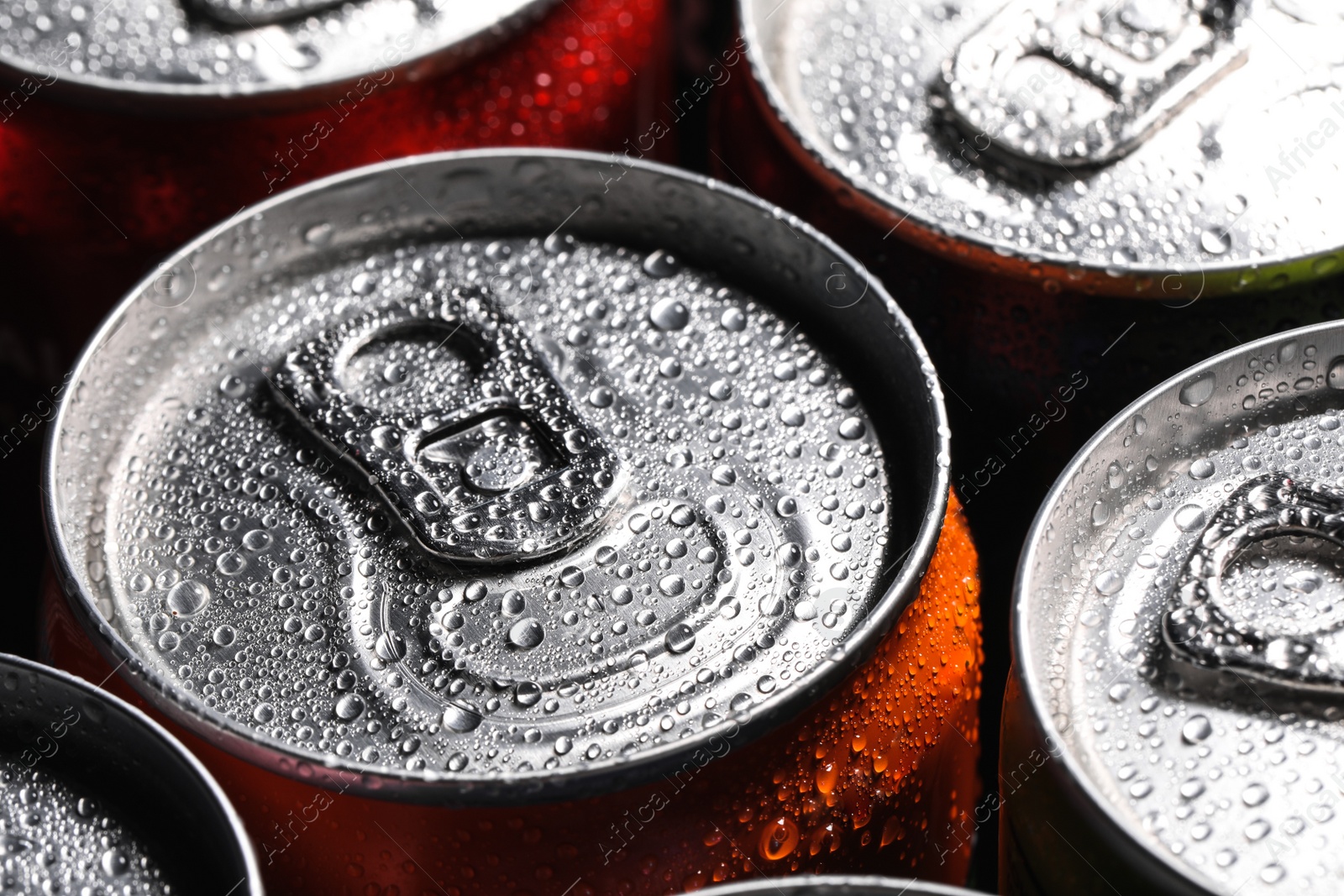 Photo of Aluminum cans of beverage covered with water drops as background, closeup