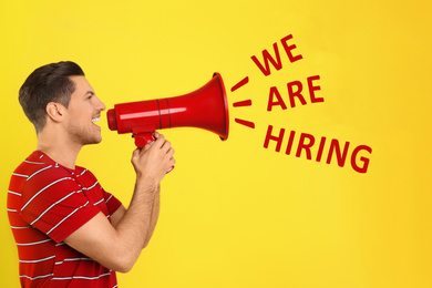 Man with megaphone and phrase WE ARE HIRING on yellow background. Career promotion