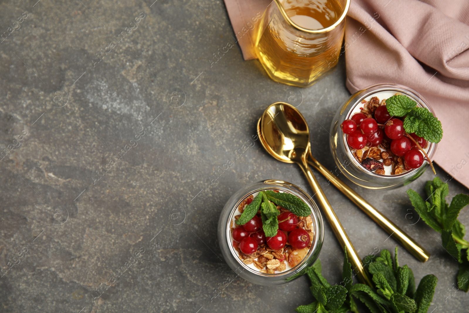 Photo of Delicious yogurt parfait with fresh red currants and mint on grey table, flat lay. Space for text