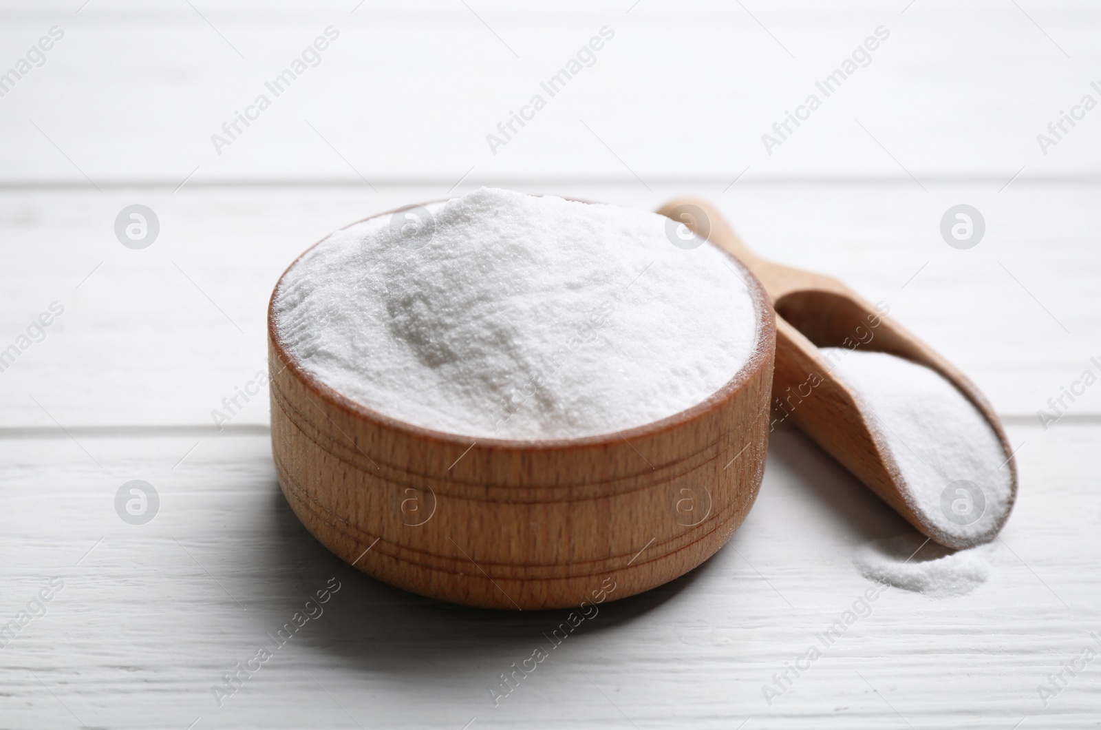 Photo of Baking soda in bowl on white wooden table
