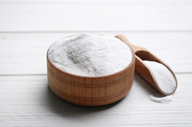 Photo of Baking soda in bowl on white wooden table