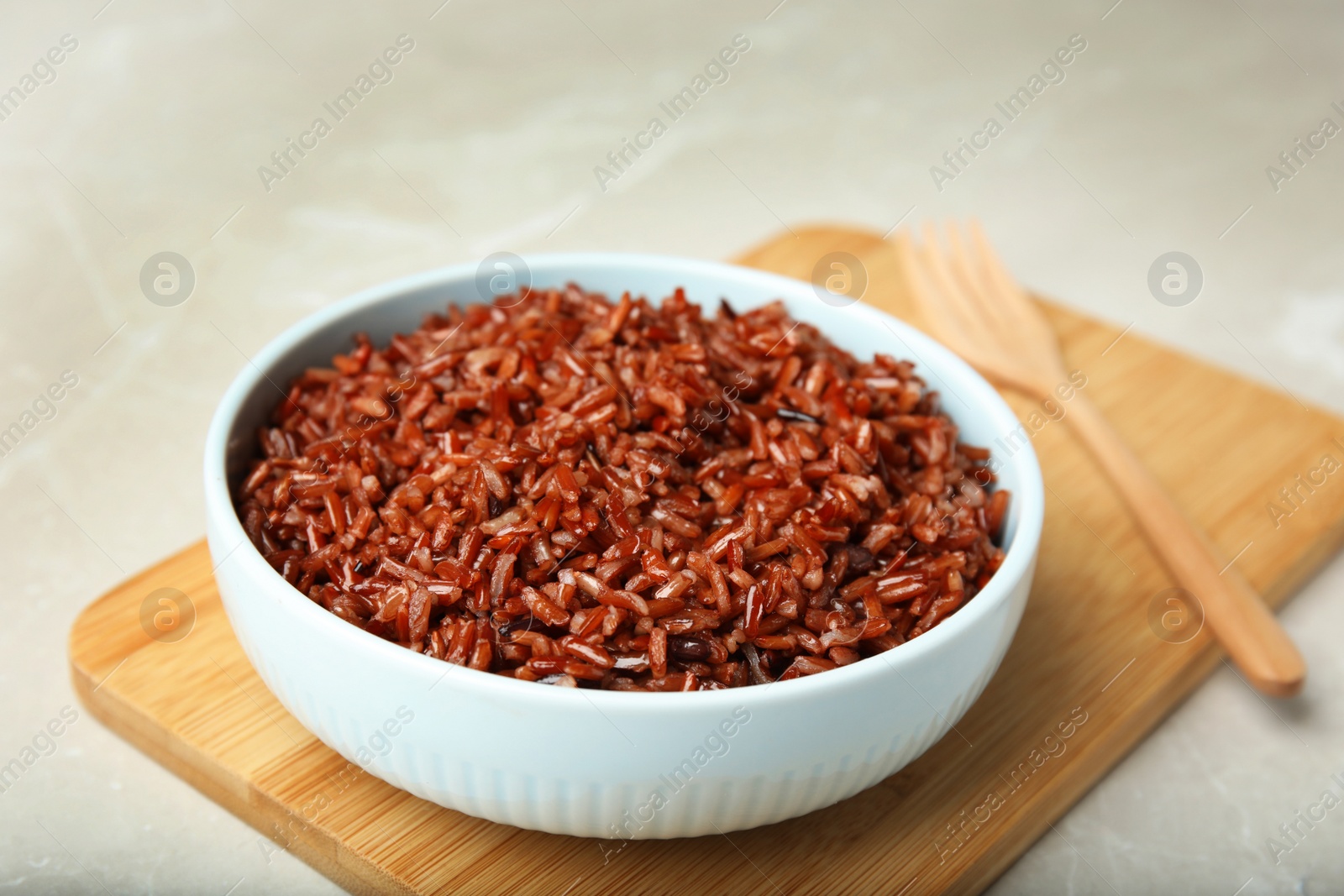 Photo of Bowl with delicious cooked brown rice on white table