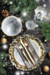 Christmas place setting for festive dinner on dark table, flat lay. Bokeh effect