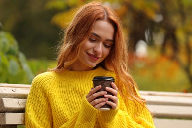 Portrait of beautiful woman with paper cup enjoying autumn outdoors