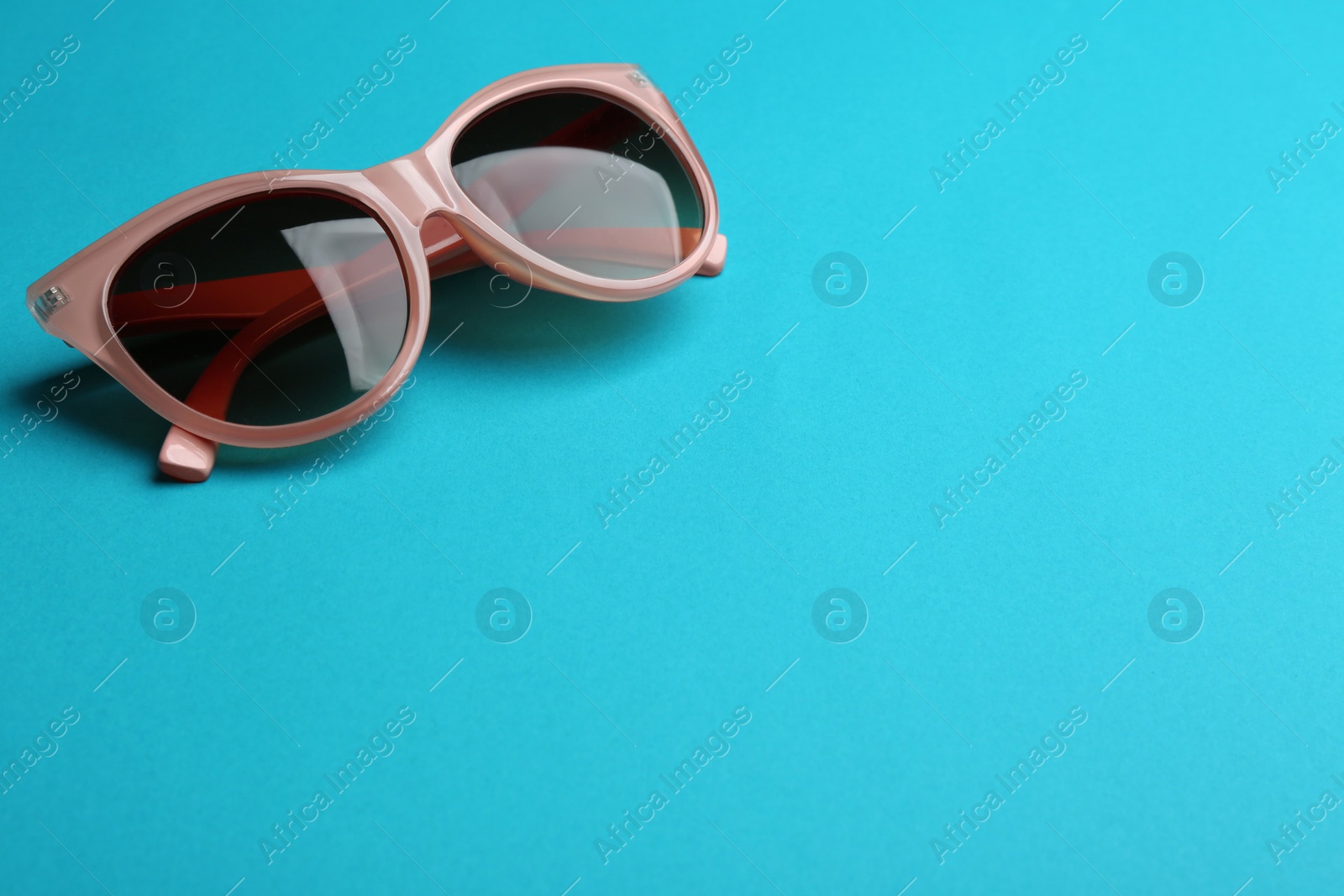 Photo of Stylish sunglasses on blue background, space for text. Fashionable accessory