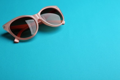 Photo of Stylish sunglasses on blue background, space for text. Fashionable accessory