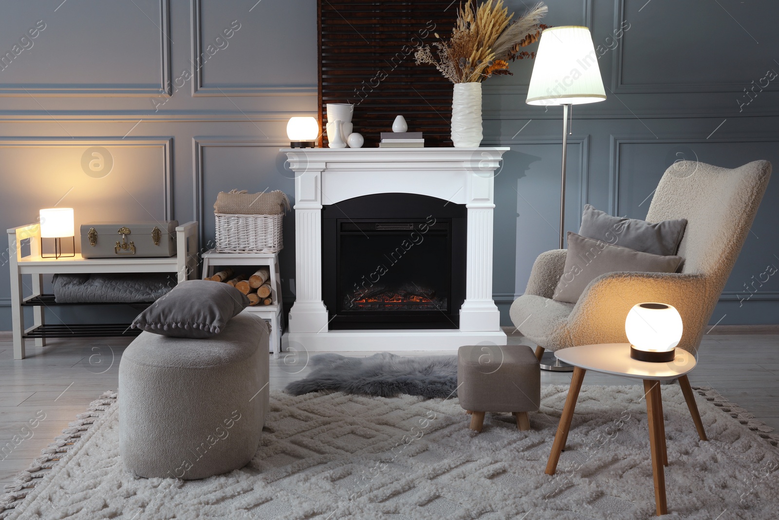 Photo of Beautiful fireplace, different decor and armchair in living room. Interior design