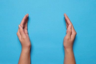 Photo of Woman holding on light blue background, closeup of hands. Space for text