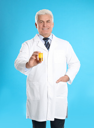 Photo of Senior pharmacist with pills on light blue background