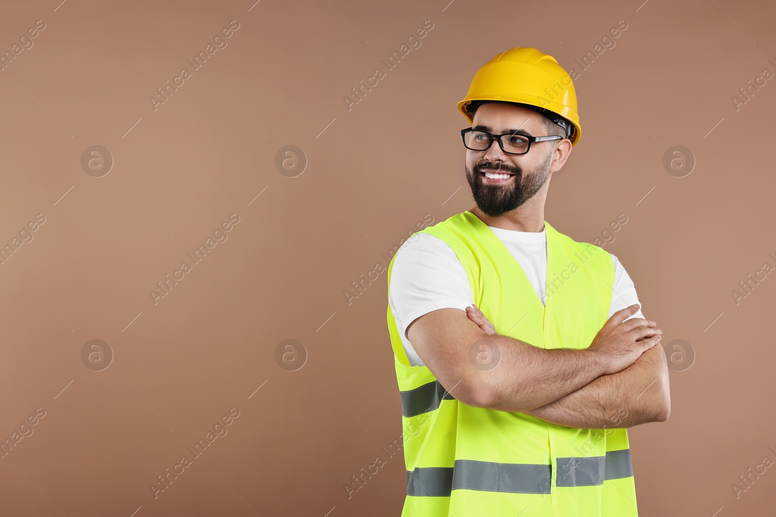 Photo of Engineer in hard hat on brown background, space for text