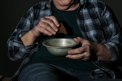 Photo of Poor senior man with bread and bowl, closeup