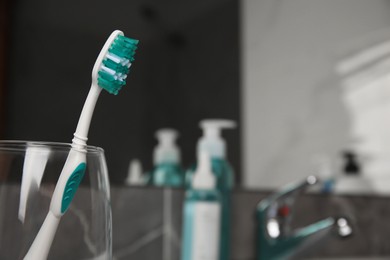 Light blue toothbrush in glass holder indoors, space for text