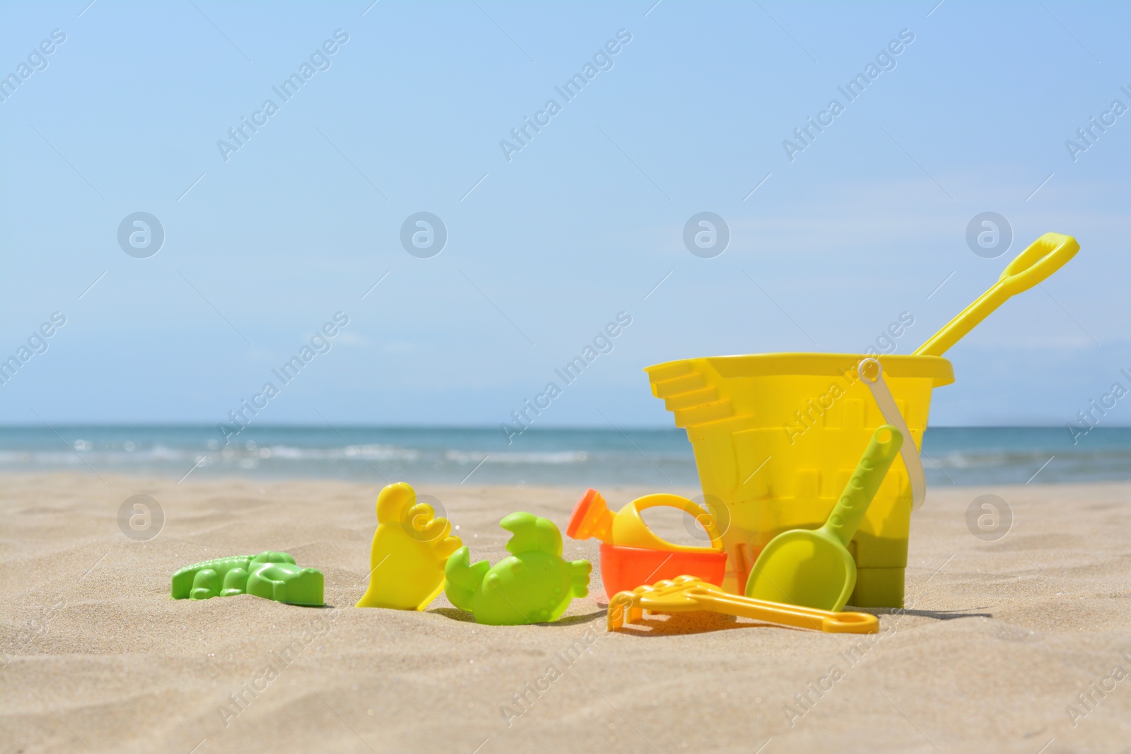 Photo of Set of colorful beach toys on sand near sea