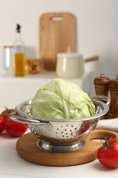 Photo of Wet cabbage in colander on white wooden table