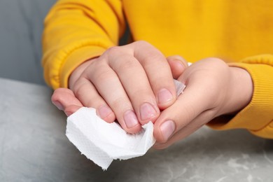 Man wiping hands with paper towel at light gray marble table, closeup
