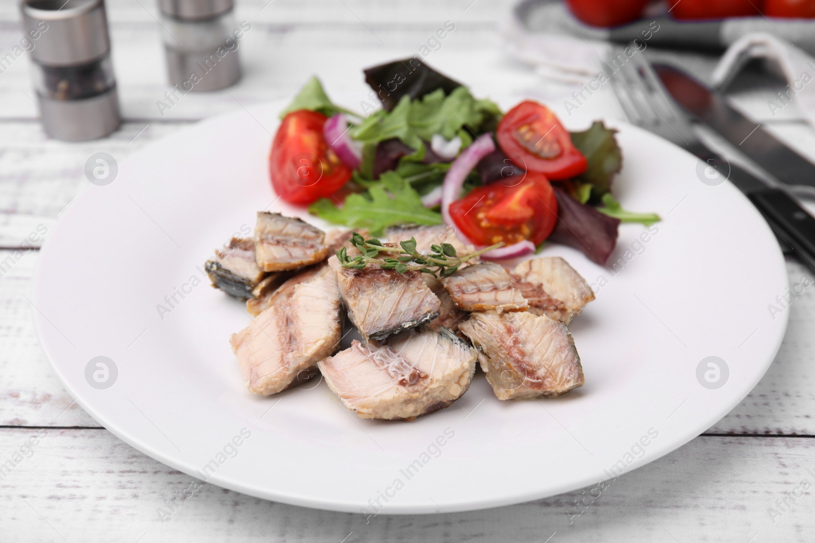 Photo of Delicious canned mackerel chunks served on white wooden table, closeup