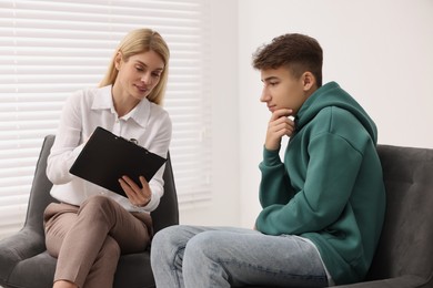 Psychologist working with teenage boy in office