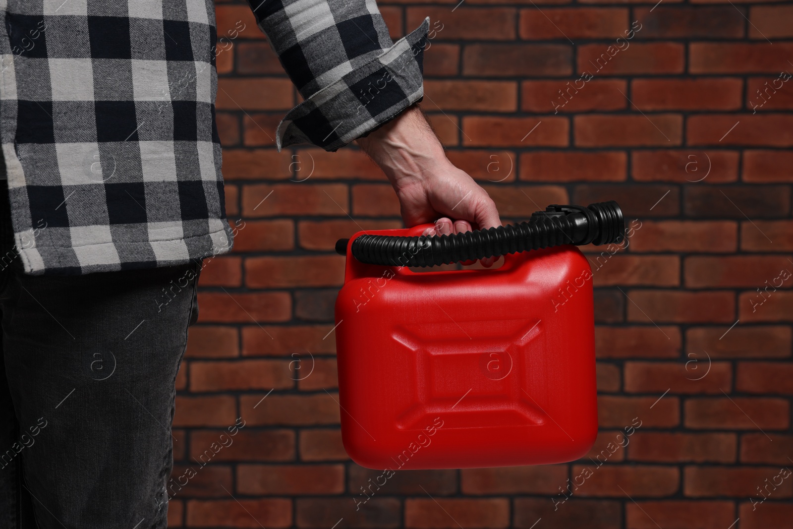 Photo of Man holding red canister against brick wall, closeup