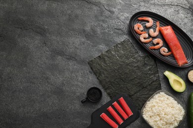 Flat lay composition with ingredients for sushi on dark textured table. Space for text