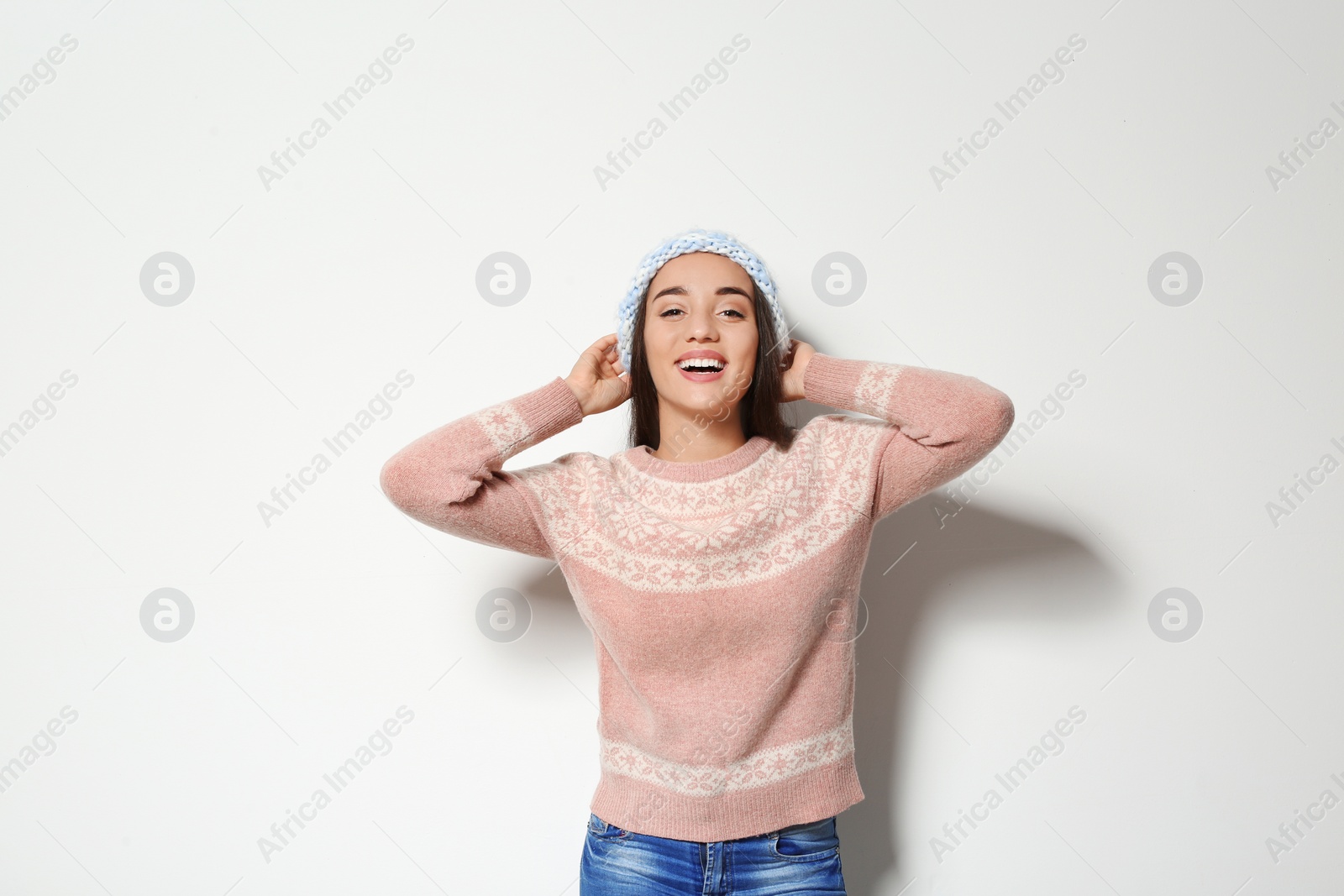 Photo of Young woman in warm sweater and knitted hat on white background. Celebrating Christmas