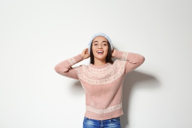 Photo of Young woman in warm sweater and knitted hat on white background. Celebrating Christmas