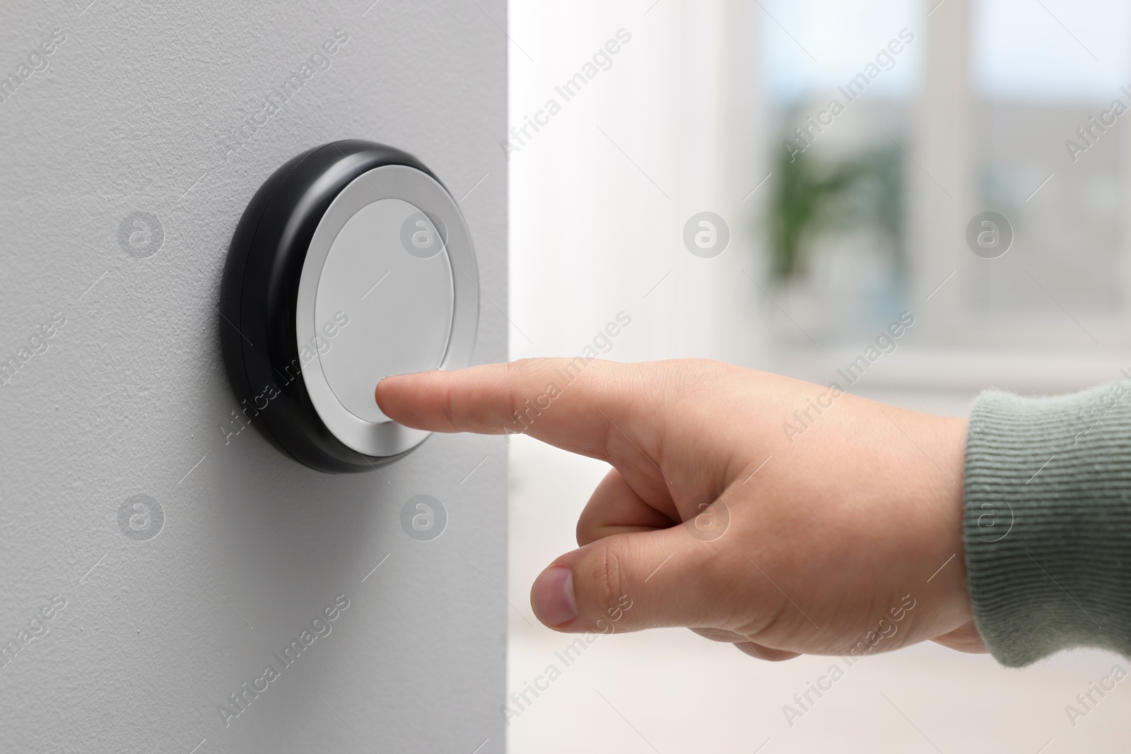 Photo of Man adjusting thermostat on white wall indoors, closeup. Smart home system