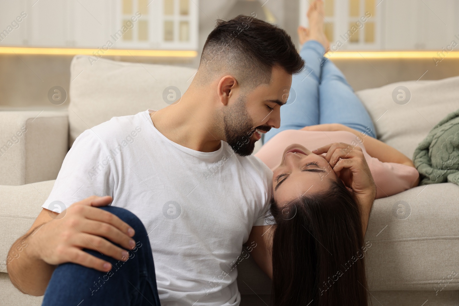 Photo of Affectionate young couple spending time together on sofa indoors