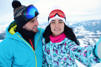 Young couple taking selfie at mountain resort. Winter vacation