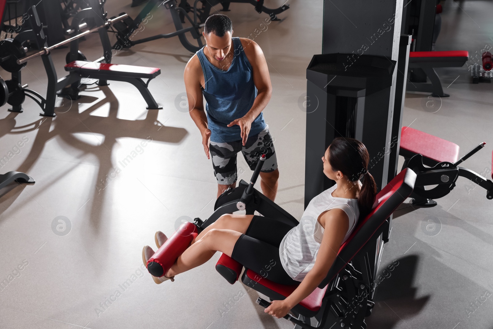 Photo of Trainer explaining woman how to do exercise properly in modern gym