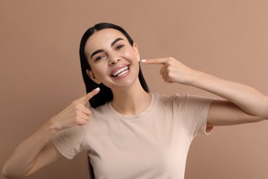 Photo of Beautiful woman showing her clean teeth and smiling on beige background