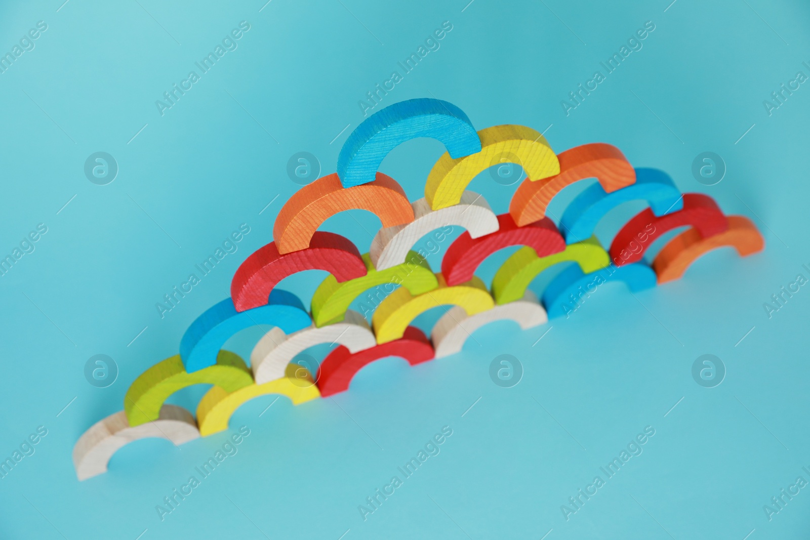 Photo of Colorful wooden pieces of playing set on light blue background. Educational toy for motor skills development