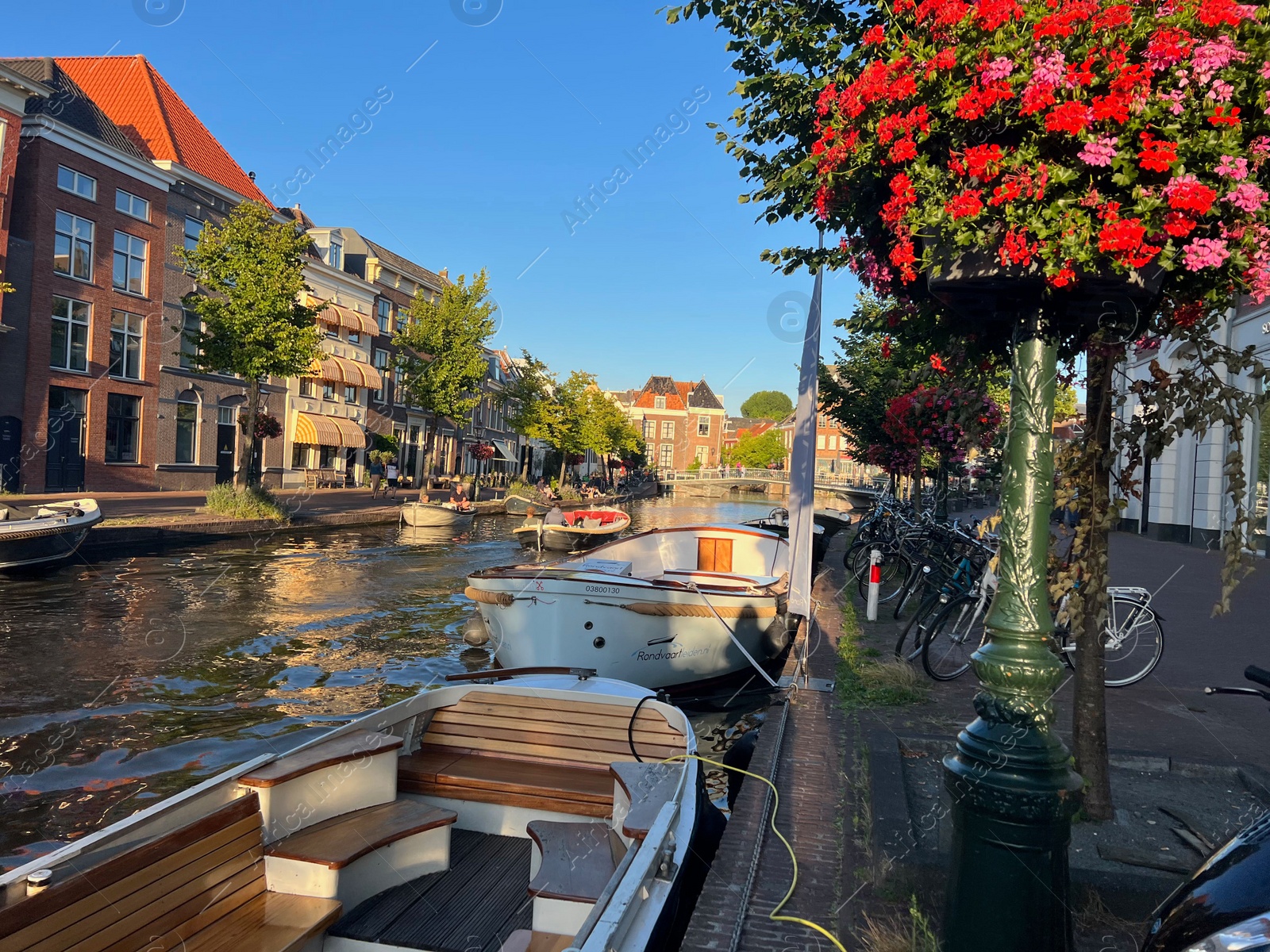 Photo of Leiden, Netherlands - August 1, 2022: Picturesque view of city canal with moored boats and beautiful buildings